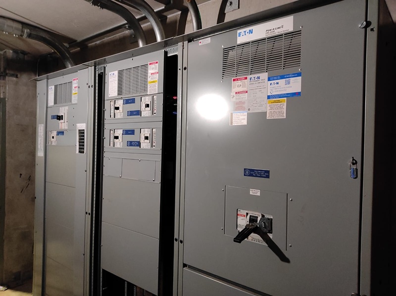 Commercial facility electrical room with labeled electrical distribution panels.