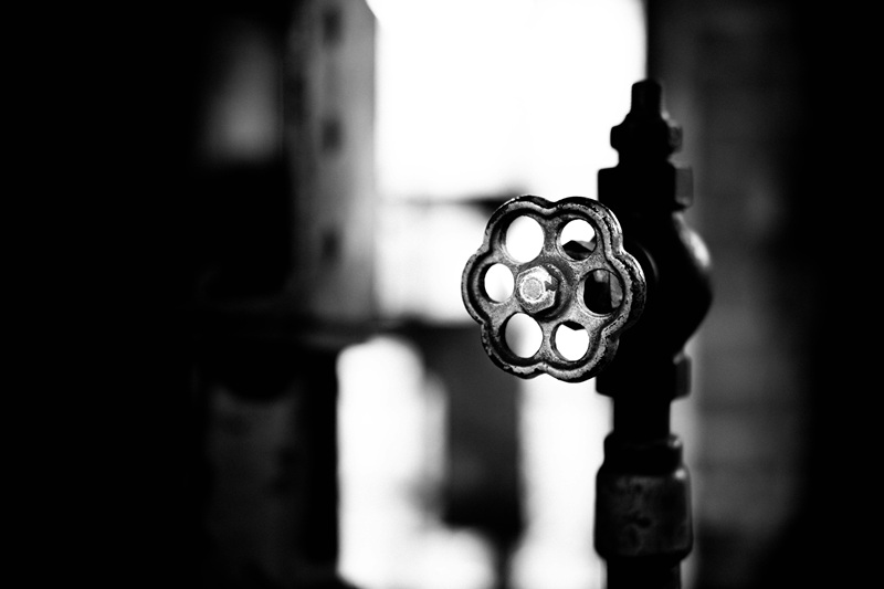 Commercial plumbing technician performing preventative valve maintenance in a building mechanical room.