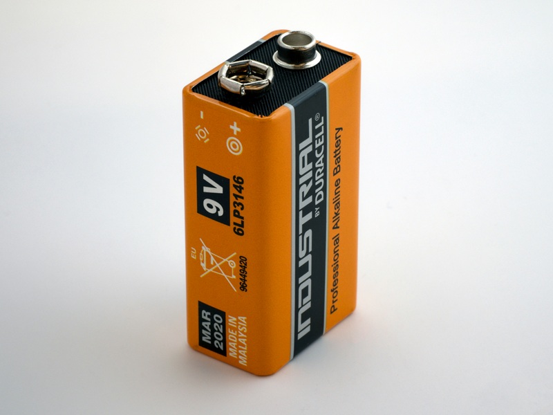 Wireless sensor with battery compartment open showing replaceable battery